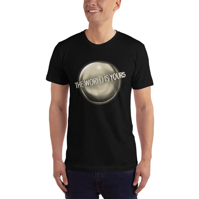 May include: Black t-shirt with a silver orb graphic and the text "THE WORLD IS YOURS" printed on it.