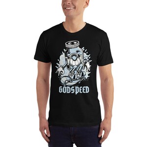 K&ouml;nnte beinhalten: Schwarzes T-Shirt mit einer Cartoon-Illustration einer blauen Flaschenfigur, die Skateboard f&auml;hrt. Der Text "GODSPEED" ist unter der Figur gedruckt.