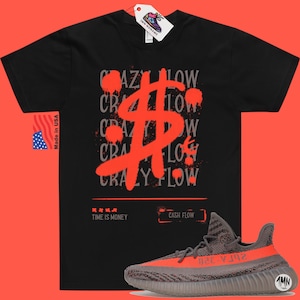 May include: Black t-shirt featuring a red dollar sign graphic and the text "Crazy Flow" repeated in grey. The shirt is paired with grey and orange trainers with the text "26ГА-320" on the side.