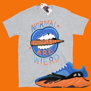 May include: A gray t-shirt with a blue mouth graphic and the text "Normal People Are Wierd". The shirt is paired with blue and orange sneakers.