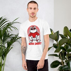 Puede incluir: Camiseta blanca con un gato de dibujos animados con gafas de sol y una sudadera roja sentado en un inodoro. El texto "WORK $MART" est&aacute; impreso debajo del gato.