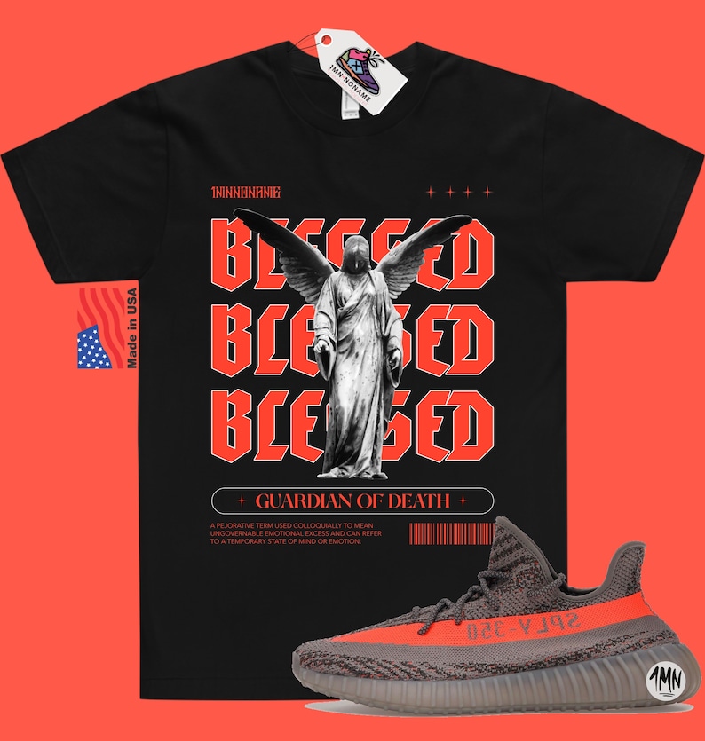 May include: Black t-shirt with a red graphic of an angel with wings and the text "Blessed" repeated three times. The text "Guardian of Death" is below the graphic. A pair of gray and orange sneakers are in the bottom right corner of the image.