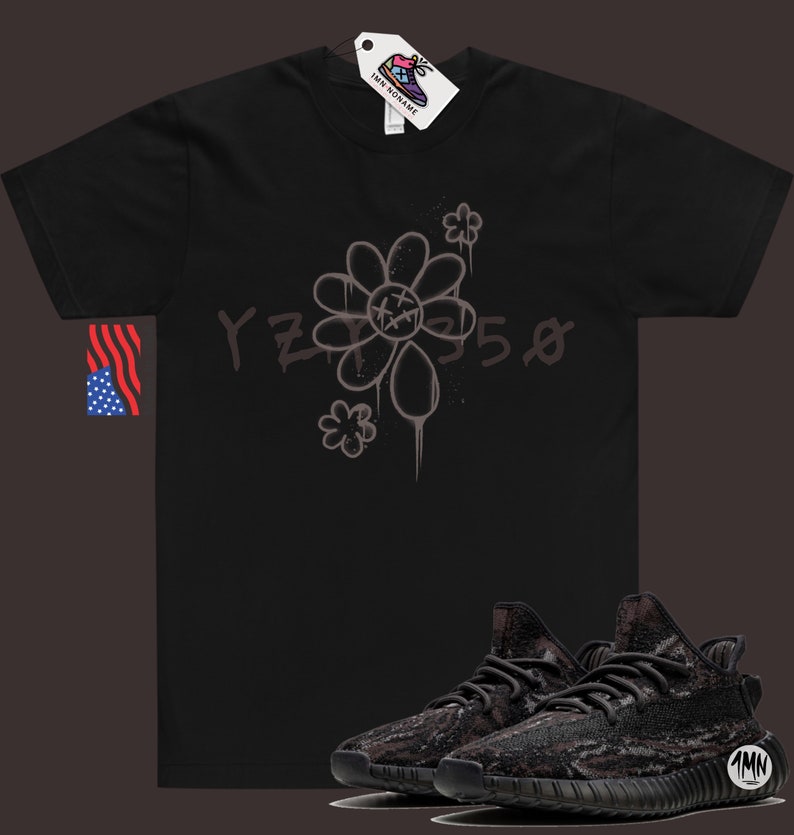 Pode incluir: Camiseta preta com um gr&aacute;fico de flor cinza e o texto "YZY 550". Um par de t&ecirc;nis preto e cinza com padr&atilde;o de camuflagem.