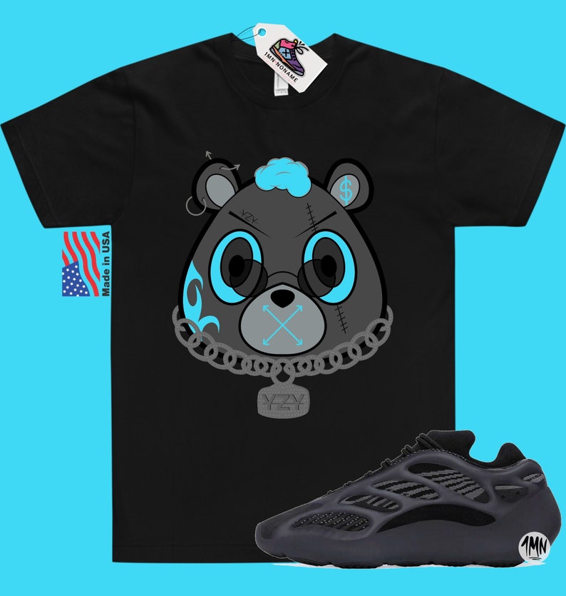 May include: Black t-shirt featuring a cartoon bear graphic with blue eyes, a chain, and the text "YZY". A pair of black and grey sneakers with a mesh design are also shown.