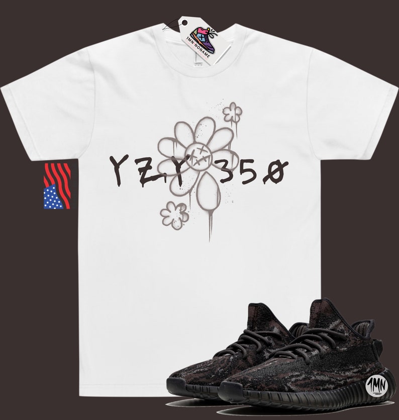 Pode incluir: Camiseta branca com um gr&aacute;fico preto e branco de uma flor e o texto "YZY 350". Abaixo da camiseta, &eacute; mostrado um par de t&ecirc;nis preto e marrom com padr&atilde;o de camuflagem.