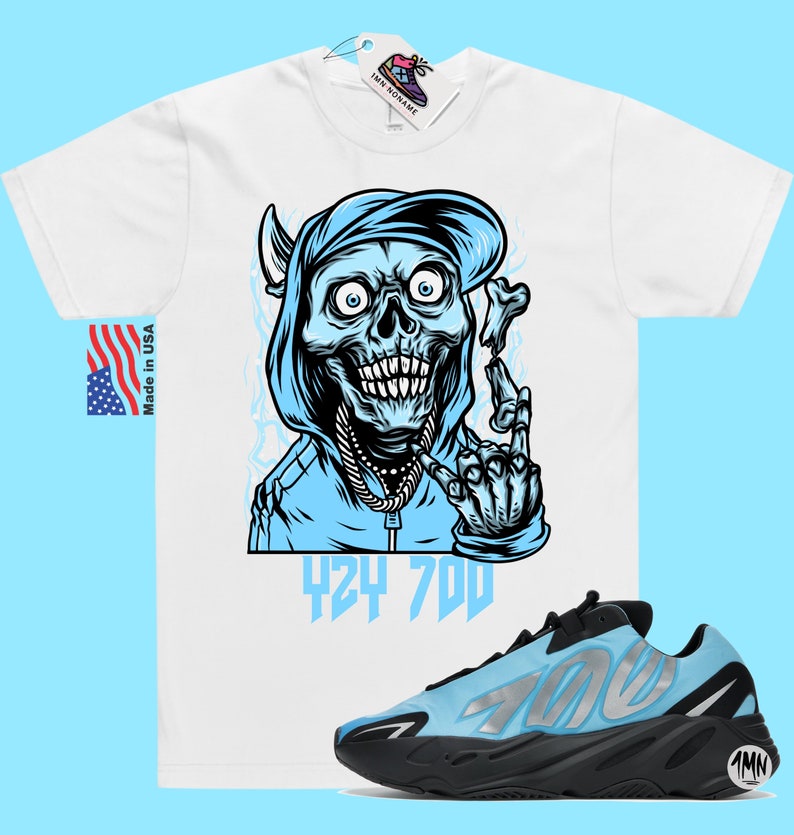 May include: White t-shirt with a blue cartoon skull wearing a blue hoodie and a gold chain. The skull is holding a bone in its right hand and making a peace sign with its left hand. The text "424 700" is printed below the skull. A pair of blue and black Adidas Yeezy 700 sneakers are shown below the t-shirt.