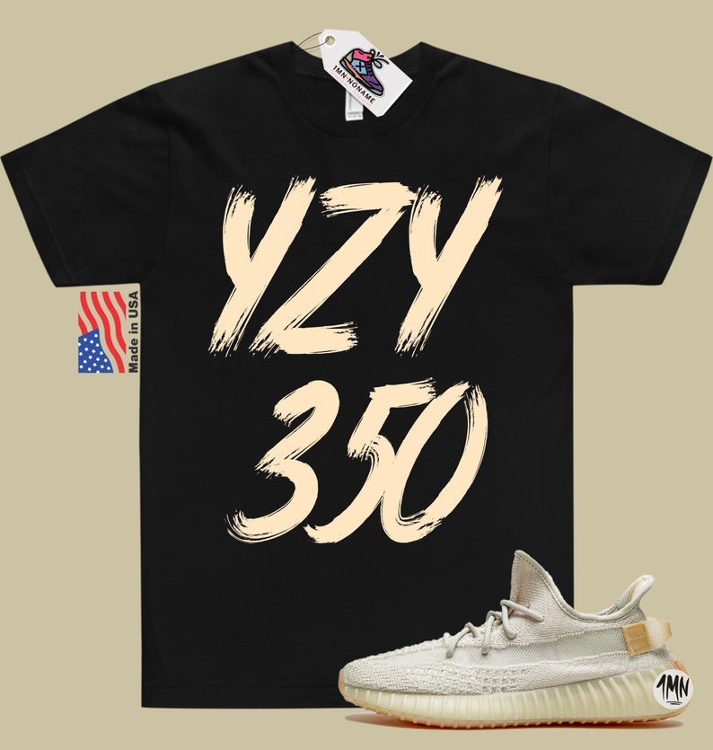 Peut inclure: T-shirt noir avec le texte "YZY 350" en couleur cr&egrave;me. Une paire de baskets cr&egrave;me avec une semelle marron est repr&eacute;sent&eacute;e sous le t-shirt.