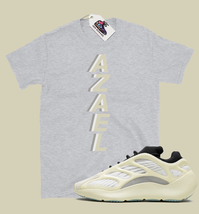 May include: A grey t-shirt with the word "AZAEL" printed vertically in a light beige color.  A pair of off-white sneakers with black accents.