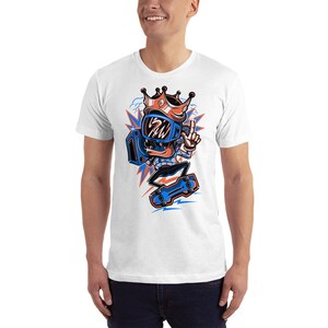 Pu&ograve; includere: Maglietta bianca con un'illustrazione di un cartone animato di una persona che indossa un casco blu e una corona, tiene un boombox e fa skateboard. La persona indossa una camicia a motivi blu e bianchi.