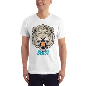 May include: White t-shirt featuring a detailed illustration of a tiger's head with an open mouth, showcasing its teeth. The word "BEAST" is printed in turquoise below the tiger's head. The design is centered on the shirt.