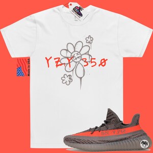 May include: White t-shirt with a gray flower graphic and the text "YZY 350" in red. A pair of gray and orange Yeezy 350 sneakers are shown below the t-shirt.