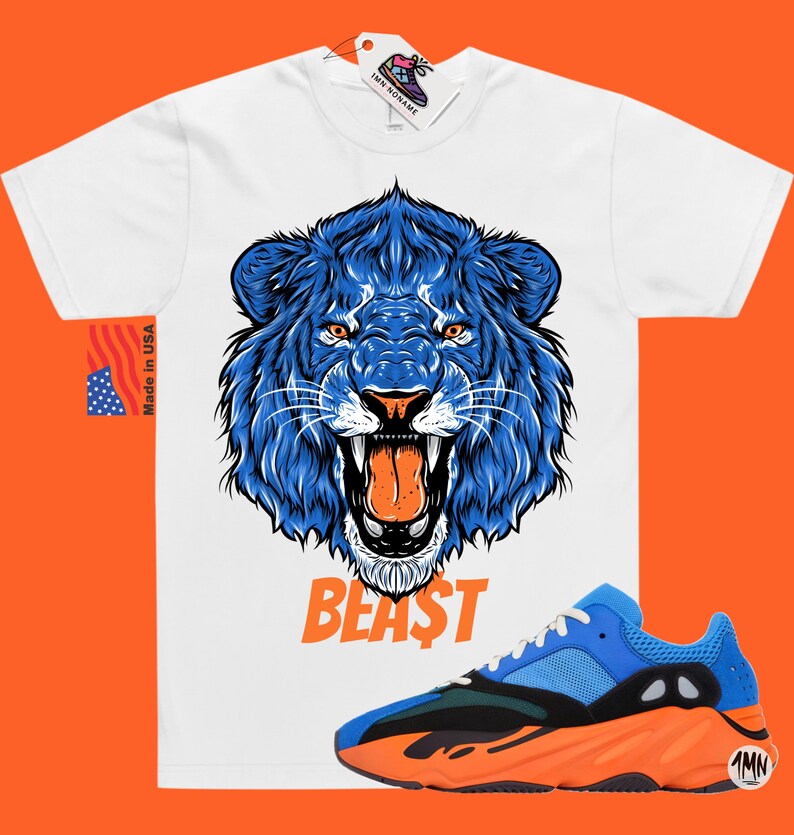 May include: White t-shirt with a blue lion graphic and the word "BEAST" printed below. The shirt is paired with blue and orange sneakers.