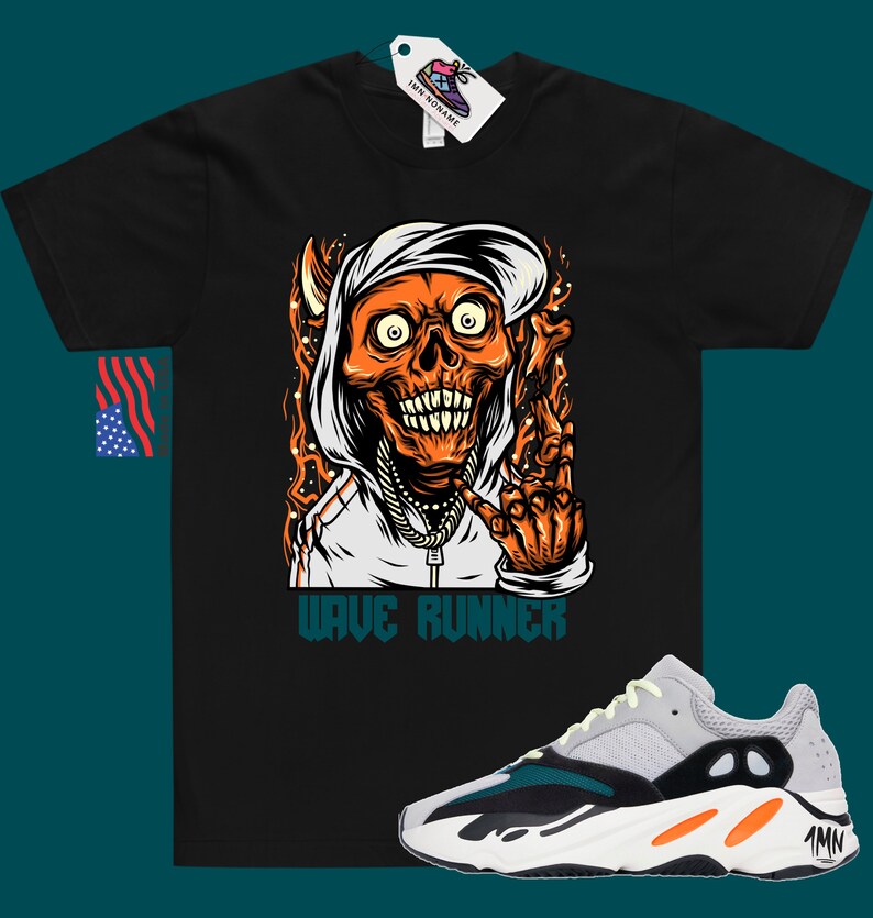 Puede incluir: Camiseta negra con un gr&aacute;fico de una calavera con capucha y una cadena de oro. El texto "Wave Runner" est&aacute; impreso debajo del gr&aacute;fico. Un par de zapatillas grises, negras y naranjas con el texto "Yeezy" en el lateral.