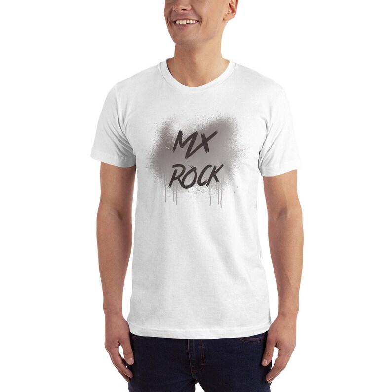 以下が含まれることがあります： グレーの吹き付けデザインと黒い「MX ROCK」の文字が入った白いTシャツ