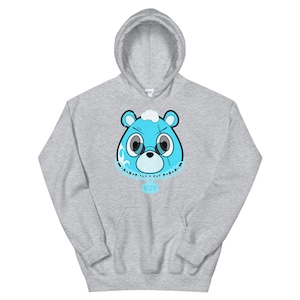 May include: A gray hoodie with a blue cartoon bear head wearing a chain with a YZY pendant. The bear has stitches on its face and a white cloud on its head.