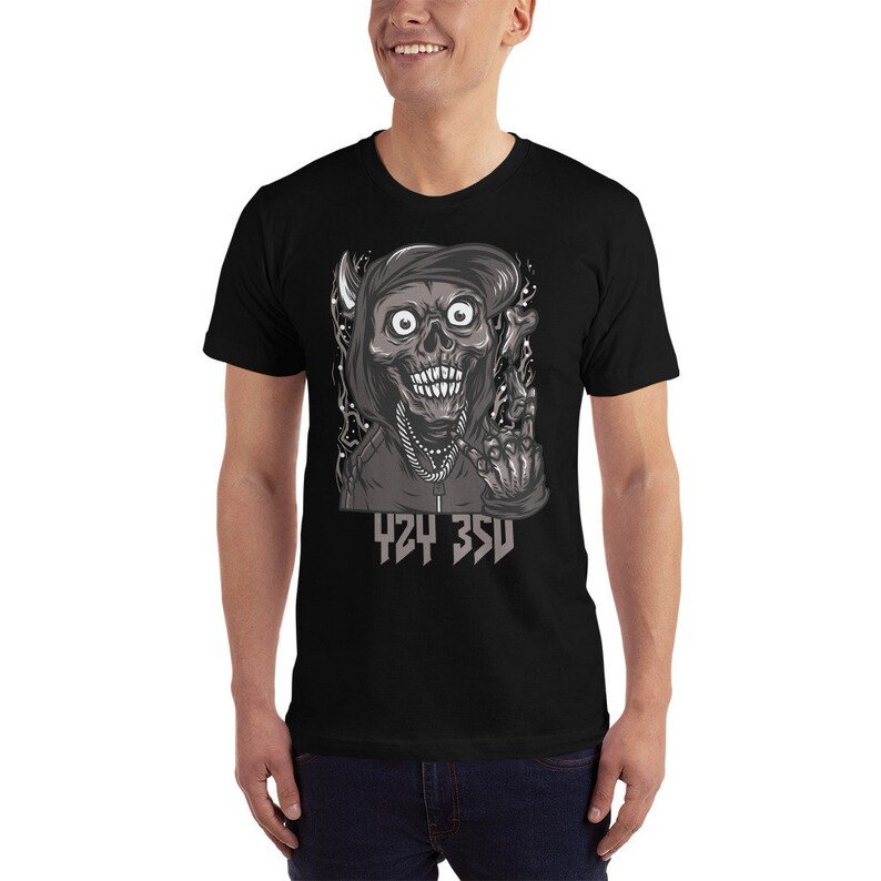 Puede incluir: Camiseta negra con un gr&aacute;fico de una calavera de dibujos animados con una capucha y haciendo un signo de paz. El texto "424 35U" est&aacute; impreso debajo de la calavera.