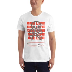 Puede incluir: Camiseta blanca con un gr&aacute;fico de calavera y huesos cruzados rojo y gris. El gr&aacute;fico se repite varias veces y dice "ONE LIFE" en letras rojas. El texto "YOU HAVE ONE CHANCE LIVE LIKE YOU'RE DYING TOMORROW 23:59:59" est&aacute; impreso en negro debajo del gr&aacute;fico.
