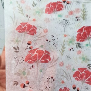 May include: White tissue paper with a floral pattern. The pattern features red flowers with green leaves and stems. There are also smaller pink and green flowers throughout the design.