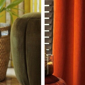 Olive ribbed velvet upholstery fabric on a rounded chair arm, paired with rust curtains in room