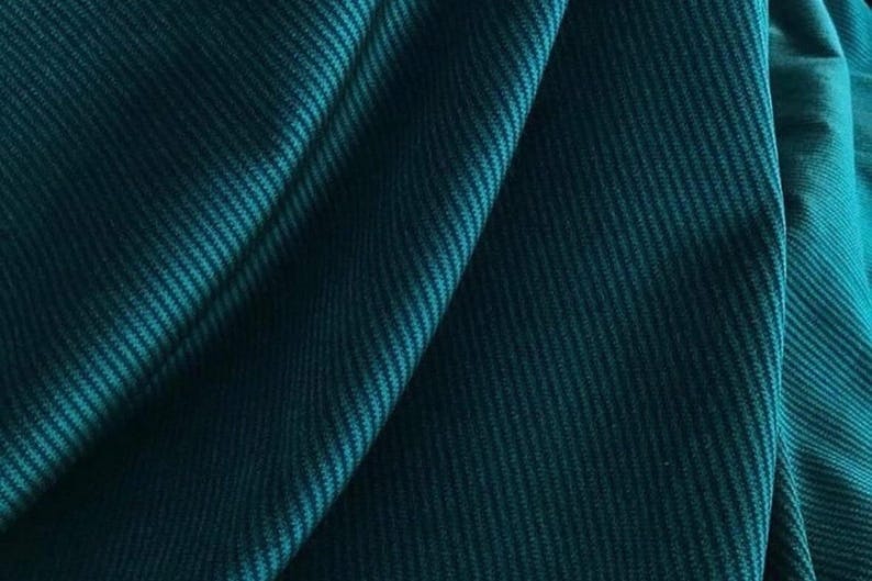 Teal draped ribbed velvet upholstery fabric, close-up folds showing deep plush ribs and sheen