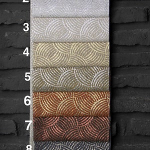 May include: Nine fabric swatches with a geometric pattern of overlapping circles. The swatches are arranged vertically, with the top swatch being a light gray and the bottom swatch being a black fabric with gold circles.