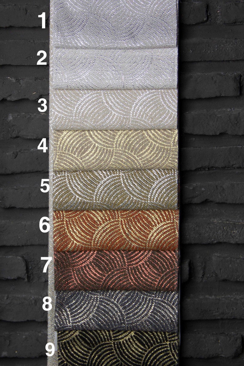 May include: Nine fabric swatches with a geometric pattern of overlapping circles. The swatches are arranged vertically, with the top swatch being a light gray and the bottom swatch being a black fabric with gold circles.