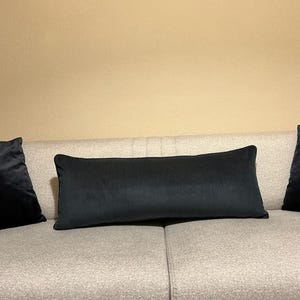 Long navy cushion in ribbed velvet upholstery fabric on a beige sofa, styled with dark accent pillows