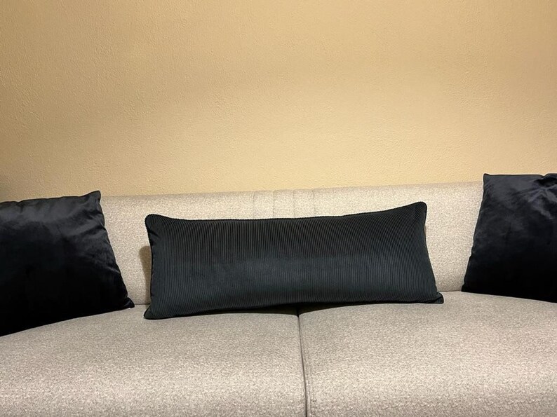 Long navy cushion in ribbed velvet upholstery fabric on a beige sofa, styled with dark accent pillows