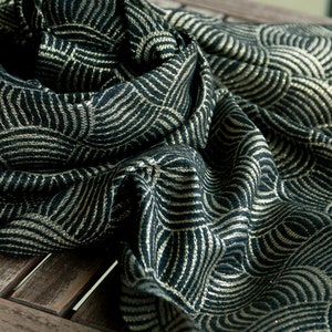 May include: A black and gold scarf with a geometric pattern of overlapping circles. The scarf is made of a soft, textured fabric.