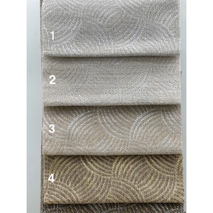May include: Four fabric swatches, numbered 1 through 4, showing different patterns and colors. The first two swatches are a solid, light beige with a subtle shimmer. The third swatch has a white, wavy pattern on a beige background. The fourth swatch has a gold, wavy pattern on a brown background.