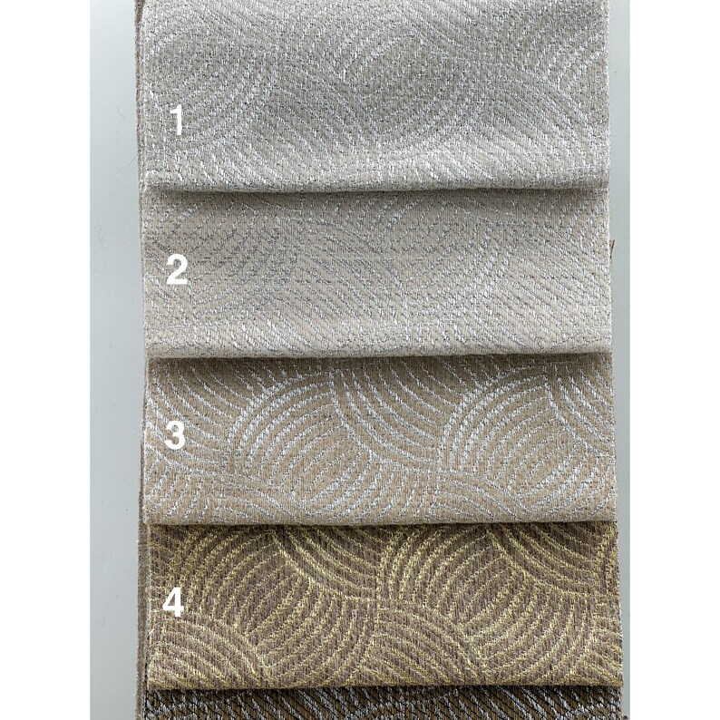 May include: Four fabric swatches, numbered 1 through 4, showing different patterns and colors. The first two swatches are a solid, light beige with a subtle shimmer. The third swatch has a white, wavy pattern on a beige background. The fourth swatch has a gold, wavy pattern on a brown background.