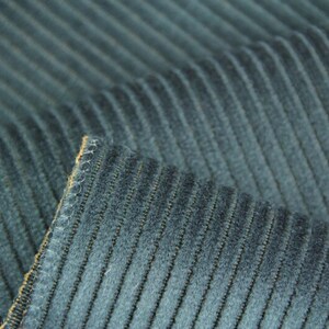 Stacked navy and gray ribbed velvet upholstery fabric swatches, stitched edge and clear rib texture