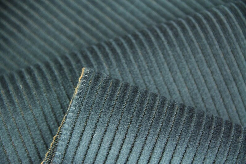 Stacked navy and gray ribbed velvet upholstery fabric swatches, stitched edge and clear rib texture