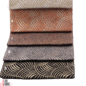 May include: Four fabric swatches with a geometric pattern in shades of beige, orange, brown, and black. The fabric has a subtle shimmer and a textured surface.
