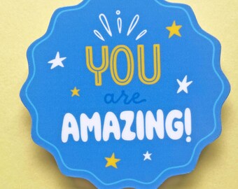Puede incluir: Pegatina azul y amarilla con un borde blanco festoneado. La pegatina dice "You are amazing!" con un diseño de estrella y estrellas alrededor del texto.