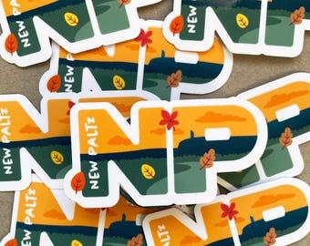 Puede incluir: Un conjunto de pegatinas con una ilustración estilizada de las letras "NP" con una escena de paisaje detrás. Las letras son de color verde oscuro, y el paisaje está en tonos de naranja, amarillo y verde. El texto "NEW PALTZ" está escrito en blanco en las pegatinas.