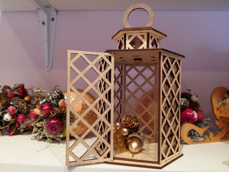 May include: A wooden lantern with a diamond-shaped lattice design. The lantern has a hinged door and a small opening at the top. The lantern is decorated with small, golden ornaments.