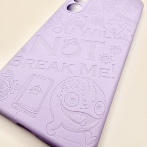May include: A light purple smartphone case featuring embossed line art illustrations including a monster, a book, and various symbols. The text "YOU WILL NOT BREAK ME!" is prominently displayed in the center, with cutouts for the camera lenses.