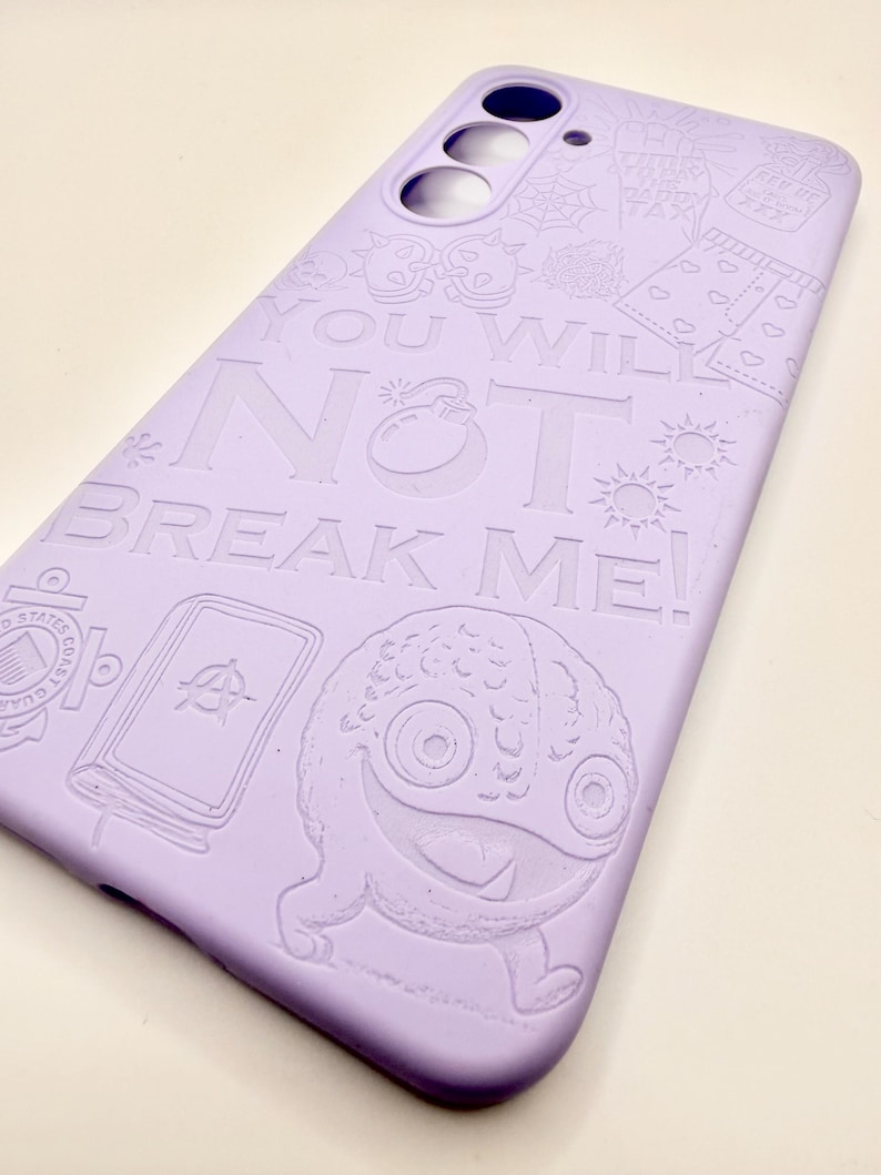 May include: A light purple smartphone case featuring embossed line art illustrations including a monster, a book, and various symbols. The text "YOU WILL NOT BREAK ME!" is prominently displayed in the center, with cutouts for the camera lenses.