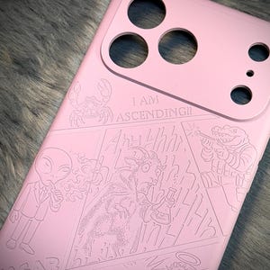 May include: Pink phone case with engraved comic-style illustrations. The case features a crab, an alien, a goat with a beaker, and a creature with a gun. Text on the case reads "I AM ASCENDING!!". The case has cutouts for the phone's camera.