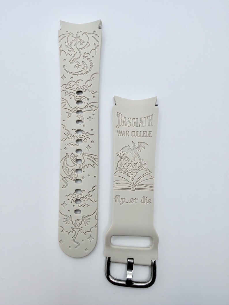 May include: A light beige silicone watch band featuring laser-engraved dragon illustrations and clouds. One strap displays the text Basgiath War College above an open book graphic and the phrase fly...or die, while the other shows multiple dragons.