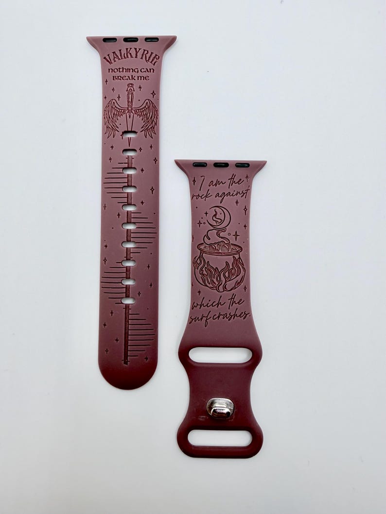 May include: A dark maroon silicone watch band featuring engraved designs. One strap displays a sword with wings and the text VALKYRIE nothing can BREAK ME. The other strap shows a cauldron, a moon, and the text I am the rock against which the surf crashes.