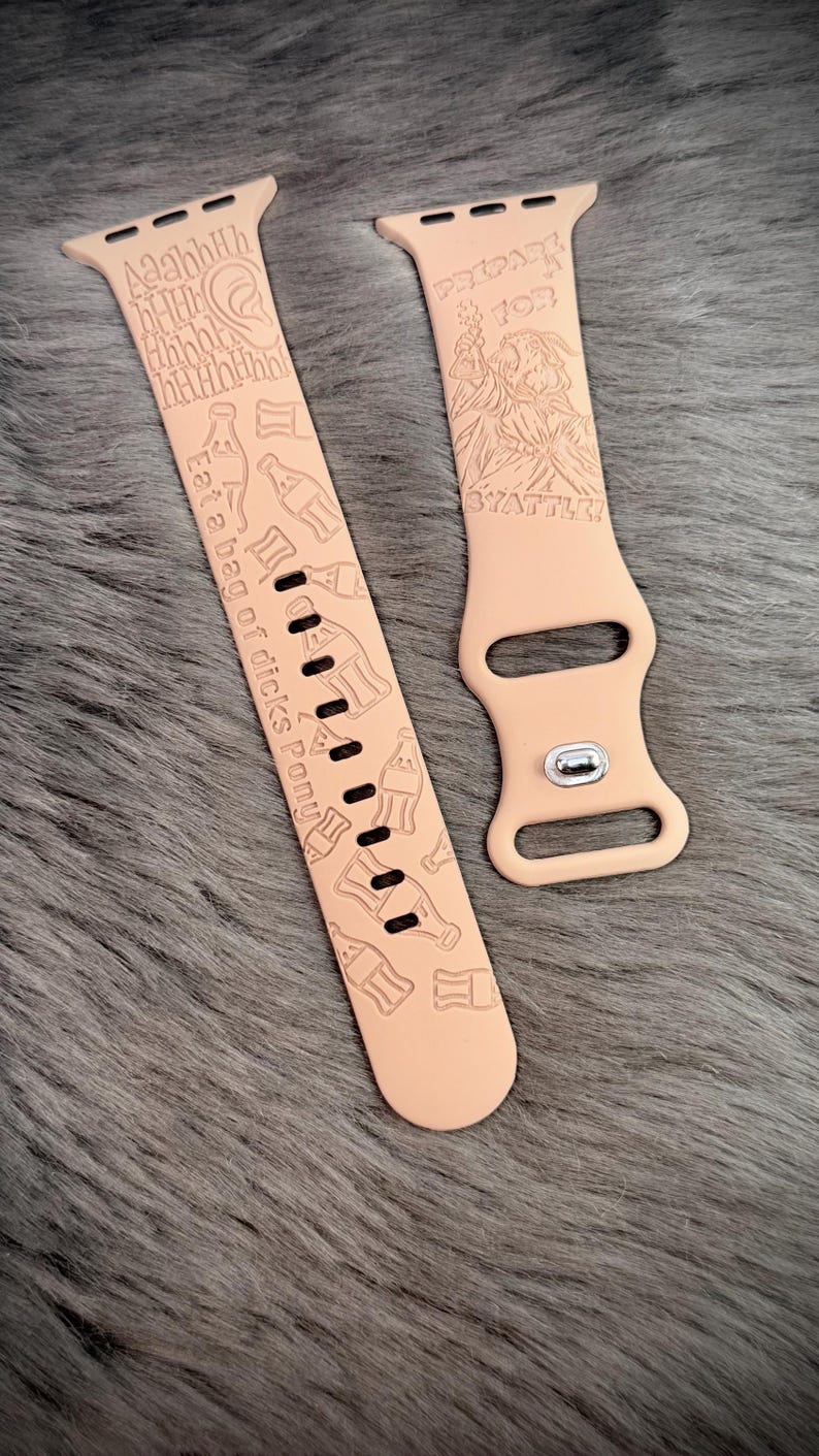 May include: A light peach-colored silicone watch band featuring laser-engraved designs including bottle shapes, an ear, and text that reads "AaahhHh", "Eat a bag of dicks Pony", and "PREPARE FOR SYATTLE!" with a graphic of a figure holding a torch.