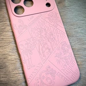 May include: Pink phone case with a comic book style design. The case features engraved illustrations of an alien, a goat, a scorpion, and other figures. Text includes "I AM ASCENDING!!", "QUASAR", and "DON'T GARLICK JESUS!".
