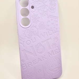 May include: A light purple phone case featuring embossed graphic designs including a skull, a spider web, a bomb, a heart-patterned pair of shorts, and the text "TIME TO PAY THE DADDY TAX", "YOU WILL NOT BREAK ME!", and "REV UP".