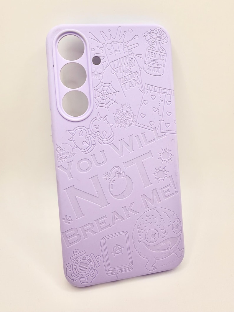May include: A light purple phone case featuring embossed graphic designs including a skull, a spider web, a bomb, a heart-patterned pair of shorts, and the text "TIME TO PAY THE DADDY TAX", "YOU WILL NOT BREAK ME!", and "REV UP".