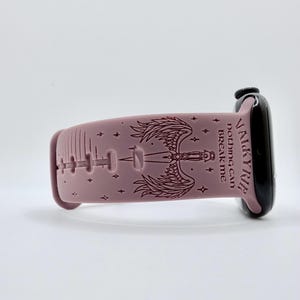May include: A dusty rose silicone watch band featuring a dark engraved design of a sword with wings, small stars, and the text VALKYRIE nothing can BREAK me. The band is attached to a black smartwatch case with a side dial visible on the right.