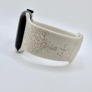 May include: A light beige silicone watch band attached to a black smartwatch case. The band features an engraved floral bouquet design and the cursive text "labor & delivery" etched into the surface, creating a textured, monochromatic appearance.