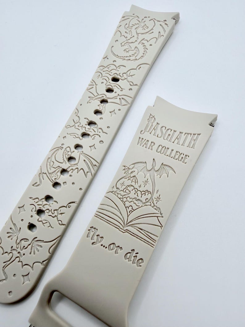 May include: A light beige silicone watch band featuring laser-engraved dragon motifs, clouds, and stars. One section displays the text "Basgiath War College" above an open book illustration with a dragon, followed by the phrase "fly...or die".