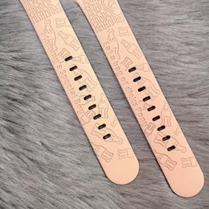 May include: A pair of light peach silicone watch bands featuring engraved patterns of soda bottles, an ear icon, the text Aaahhh, and the phrases Mommy's Special Boy and Eat a bag of dicks Pony, with standard attachment hardware at the top ends.